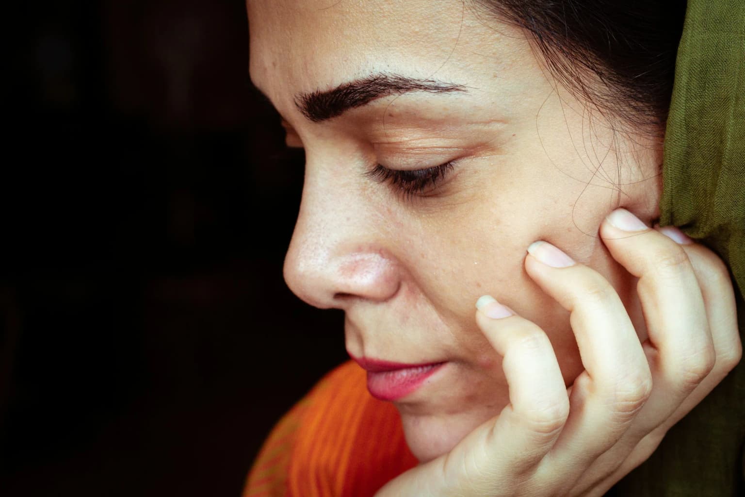 Mujer madura con la mano en la mejilla, piel natural sin maquillaje.