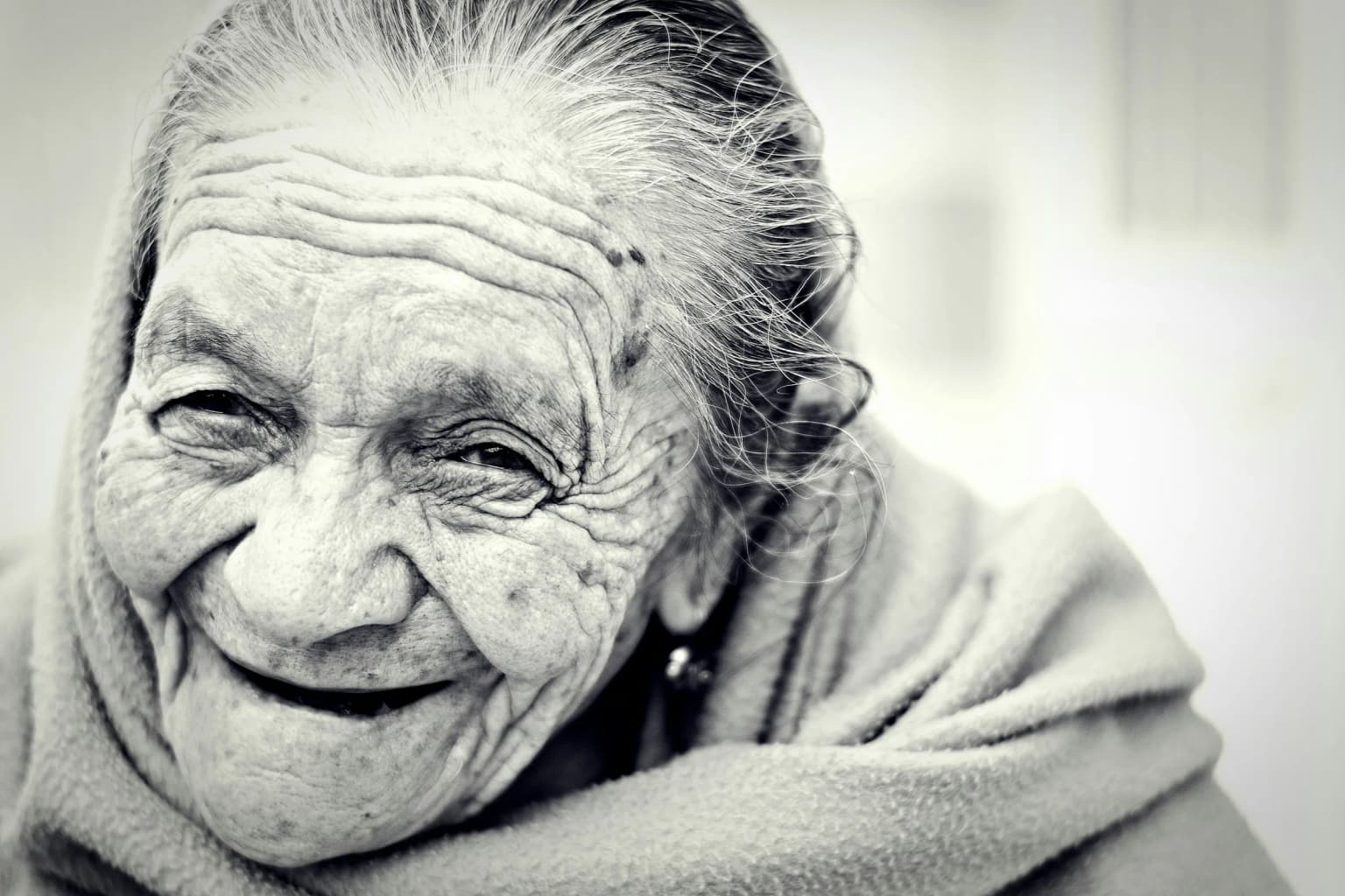 Mujer madura riendo con la piel iluminada por luz natural.