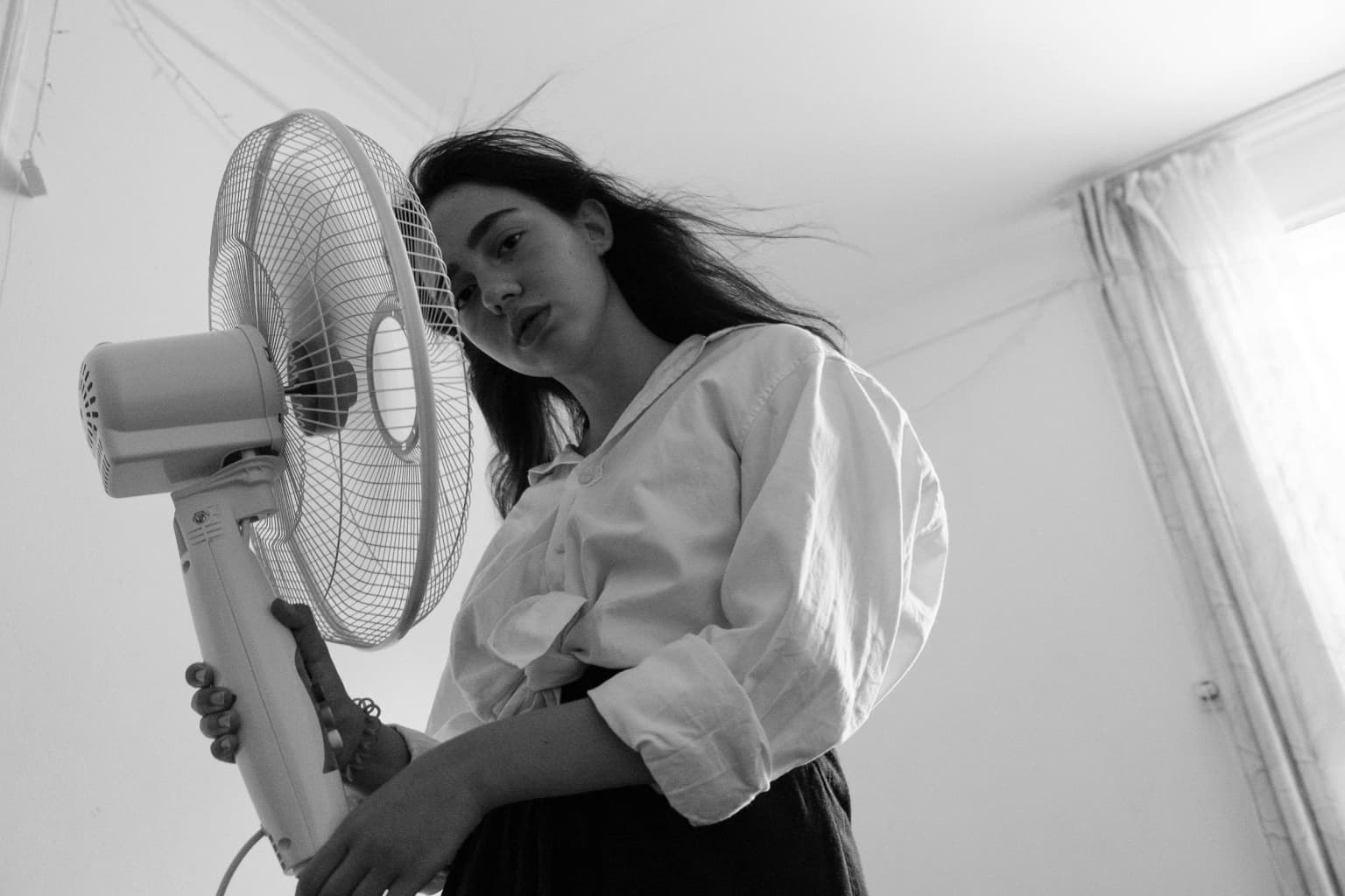 Mujer refrescándose frente a un ventilador.